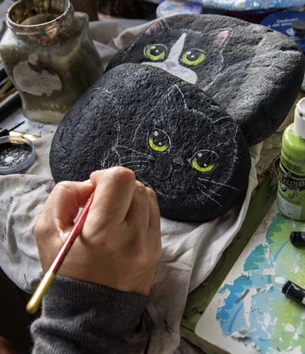 Ein Stein wird mit einer Katze bemalt